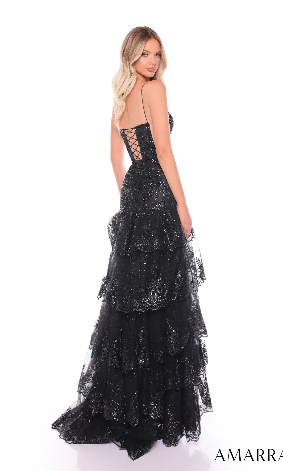 A woman poses gracefully in the Long Formal Dress 88500 by Amarra, featuring black ruffle layers, shimmering sequins, spaghetti straps, a plunging v-neckline, and a lace-up back against a white background.